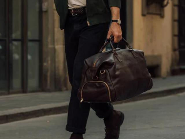 a man holding a bag and walking on a sidewalk